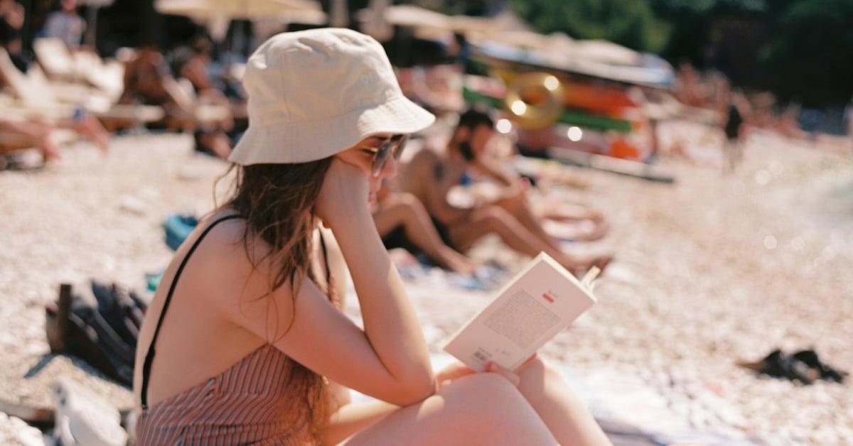 Vrouw leest boek op strand